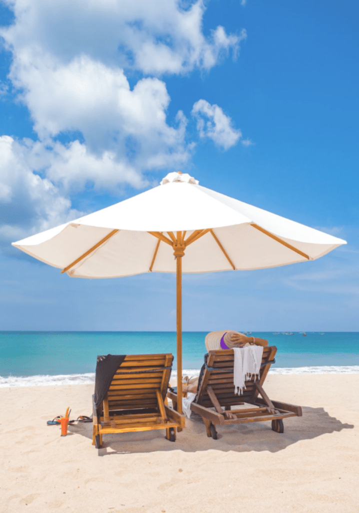 Sunbeds under a white umbrella on Lamai Beach at Three Trees Samui Resort with turquoise sea and blue sky